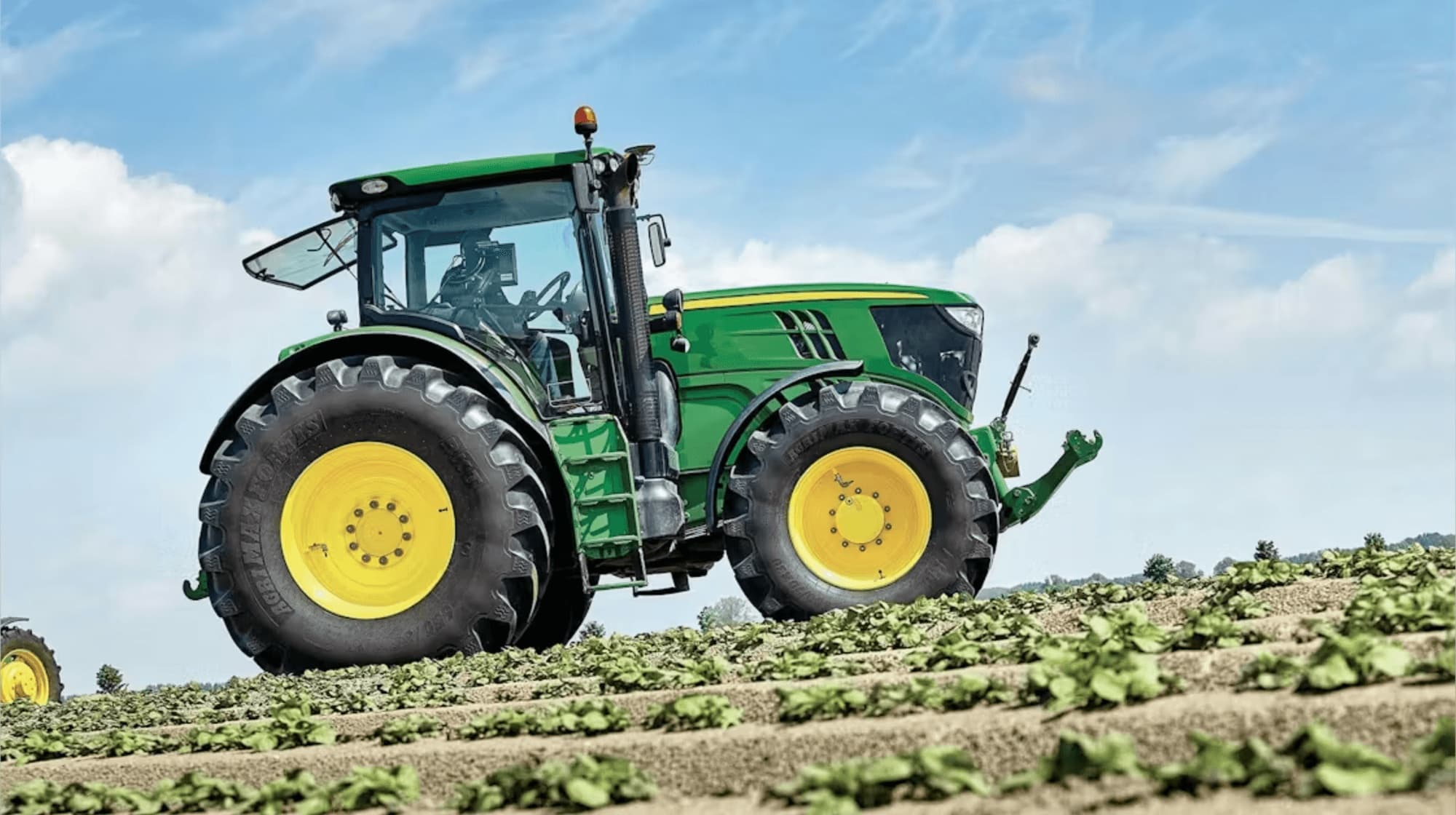 A tractor working a field of young crops