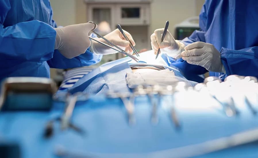 A surgical team working over a tray of instruments in an operating theatre